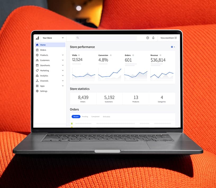 Ein Laptop, der auf einer orangefarbenen Oberfläche ein Leistungs-Dashboard eines E-Commerce-Shops anzeigt.